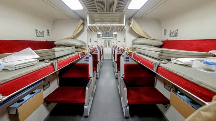 Interior view of a 1st Class private sleeper train cabin with fold-down beds and private space